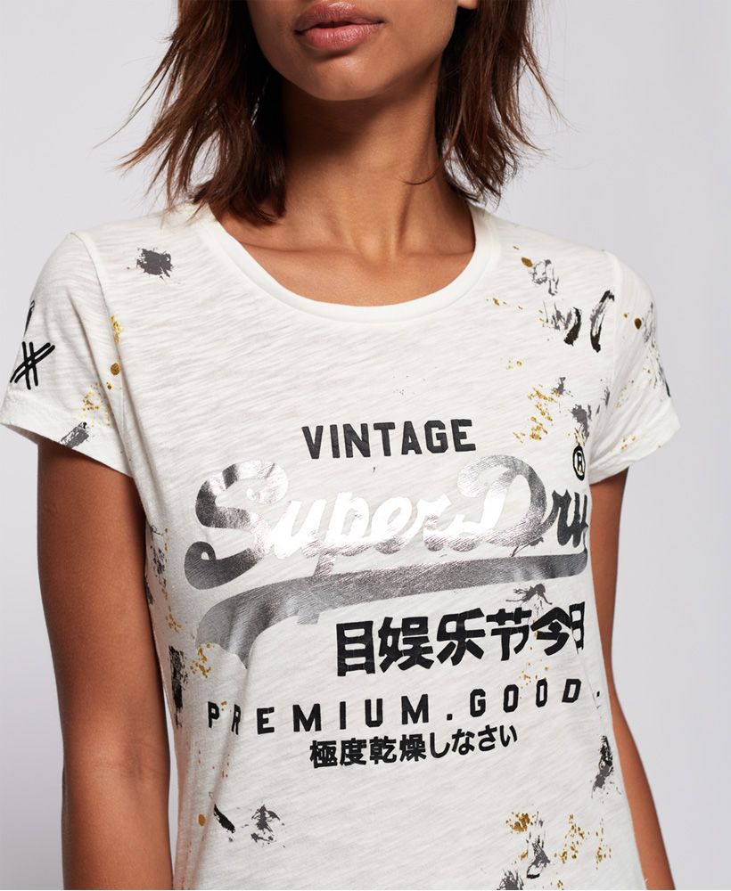 Superdry women’s premium goods doodle t-shirt. This short sleeved t-shirt features the iconic Vintage Superdry logo across the chest and a paint splatter effect all over. The t-shirt is finished a Superdry logo tab on the hem. A great addition to your wardrobe, that will look great in every season.