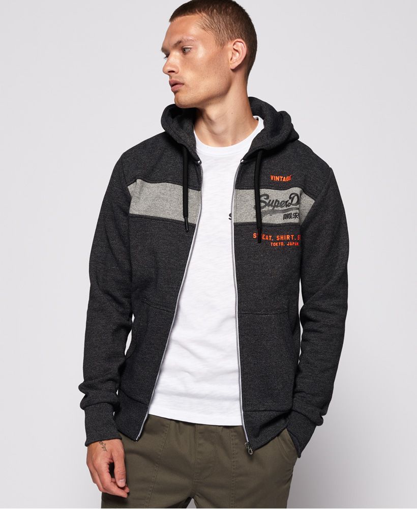 Superdry men's Sweat Shirt Shop Magma Panel zip hoodie. This hoodie features a full zip fastening, drawstring hood and front pouch pockets and ribbed cuffs and hem. Finished with a textured Superdry graphic on the front. Pair with jeans and a crew neck tee for casual styling.Slim fit