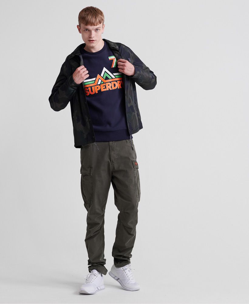 Superdry men's Downhill Racer crew jumper. This classic crew neck jumper features a textured Superdry print across the chest, and ribbed hem and cuffs. The jumper is finished with a Superdry logo tab above the hem. This jumper is the perfect addition to your wardrobe this season.Slim fit