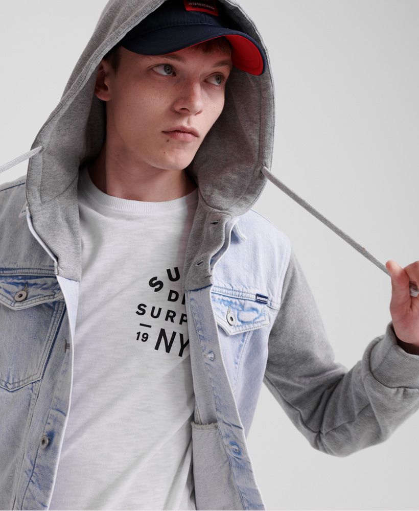 Superdry men's hooded Highwayman Trucker jacket. The Highwayman Trucker jacket features a drawstring hood, button fastening, a button adjustable hem, and four pockets. The jacket is finished with a Superdry logo patch on the pocket. Pair this jacket with a simple T-shirt for a casual layered look.