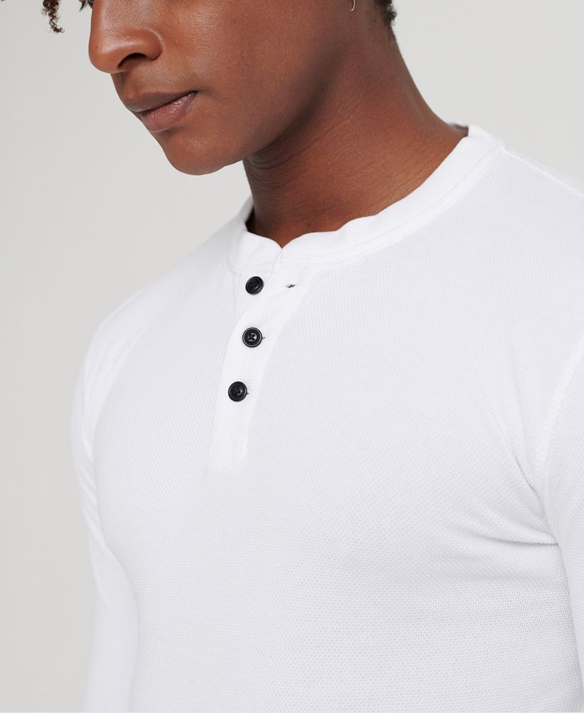 Superdry men's Edit long sleeved Henley top. This long sleeved top features a three button fastening and ribbed cuffs. Finished with a Superdry logo badge above the hem. Will look great paired with your favourite pair of jeans and a leather jacket this season.