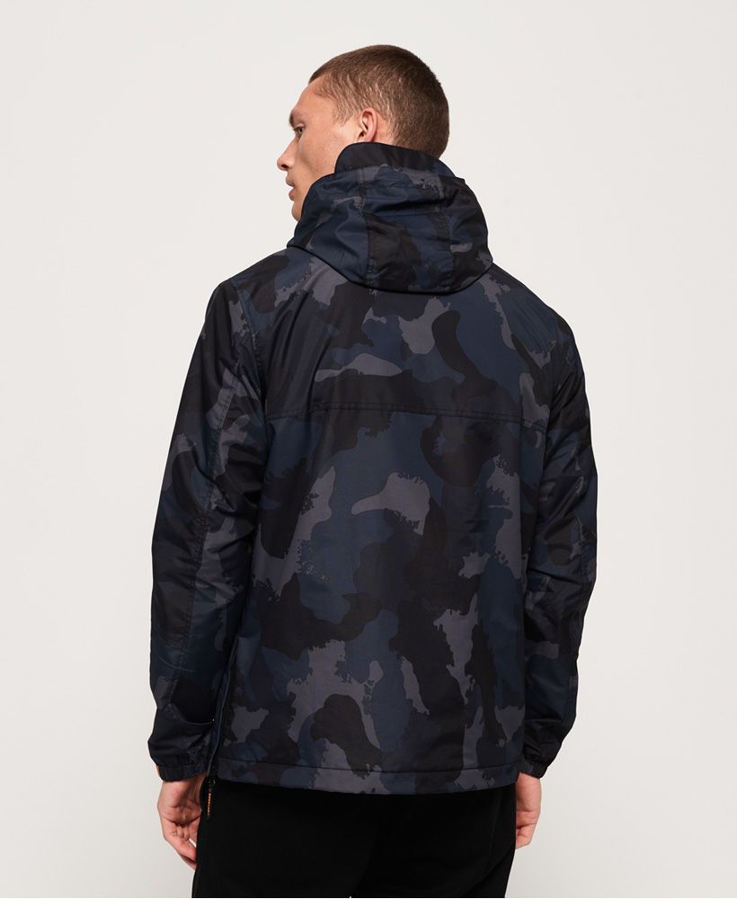Superdry men's Core overhead cagoule. This winter sports inspired cagoule will not only help to protect you from damp conditions, the fleece lined body will also help keep you warm. With bold branding across the chest flap, underneath a large pouch pocket with twin zip access and a separate zipped pocket can be found. A side zip allows you to put on or remove the cagoule more easily, while a quarter length front zip gives ventilation when required. The integral mesh-lined hood has a bungee cord adjuster along with a small peak. The cagoule is finished with a small logo patch above the hem and branded zip pullers throughout.