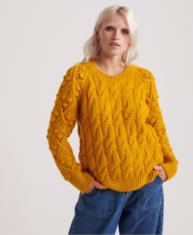 Superdry Sophie Ann Cable knit jumper. This jumper is perfect for those winter months where you want to bring the cosyness of your sofa to work. Paired with any bottoms this makes a perfect outfit. Cable knit pattern throughout and a Superdry logo tag at the hemline.