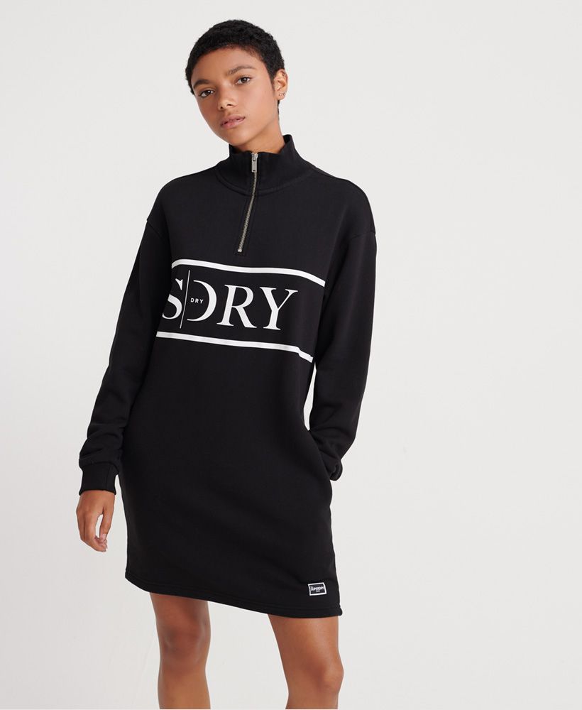 Superdry women's Edit quarter-zip sweat dress. This sweat dress features a quarter zip fastening, long sleeves, two side seam pockets and a ribbed neckline and cuffs, all finished with a simple Superdry logo print across the chest, embroidered characters below the neckline and a Superdry Edit logo above the hemline.