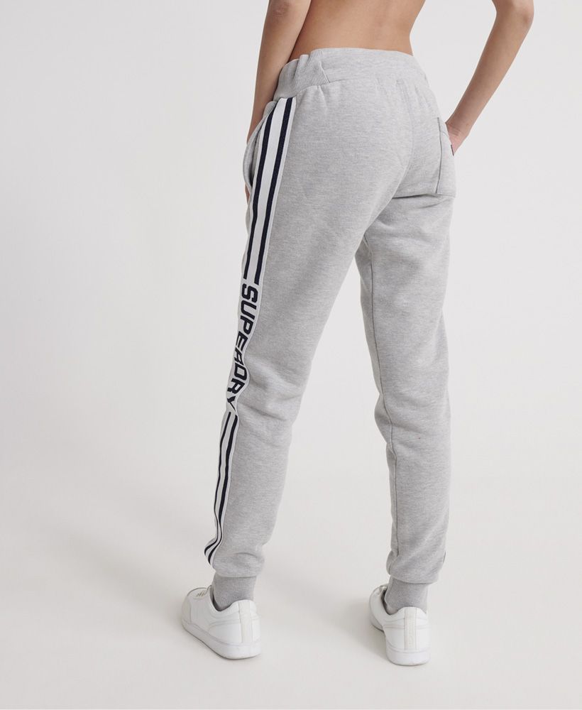Superdry women's Modern sport joggers from the Coral Label range. These joggers feature a ribbed elasticated drawstring waistband, ribbed cuffs, two front pockets and one back pocket. Complete with stripe detailing down both legs featuring a Superdry logo and a Superdry Coral Label on the back pocket. Pair the Modern Coral Label sport joggers with the matching hoodie to complete the look this season.Slim fit