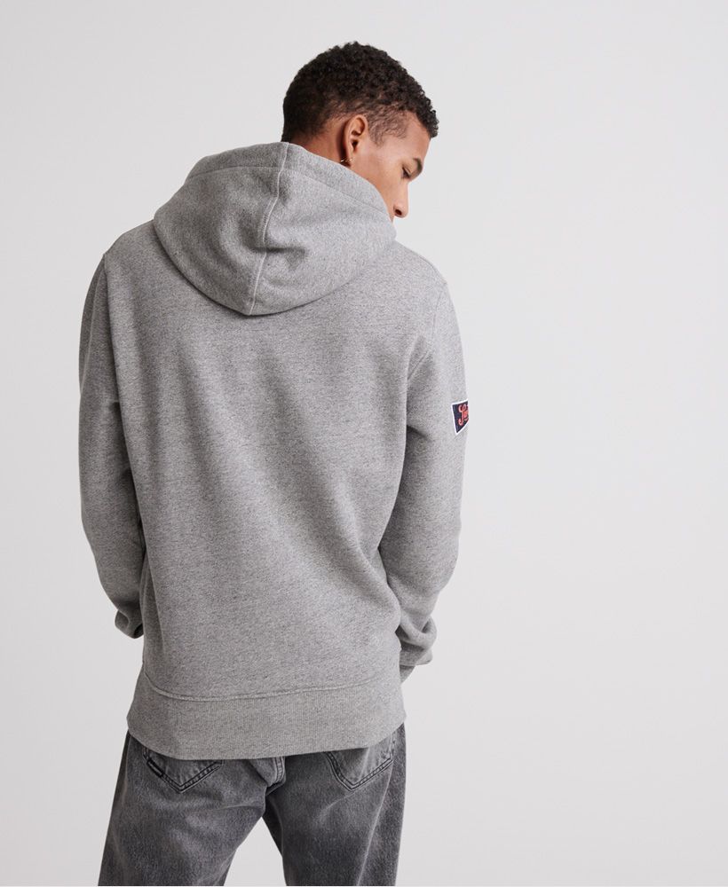 Superdry men's Classic Varsity Pennant hoodie. This hoodie features ribbed cuffs and hem, a large front pocket and a drawstring hood. Complete with embroidered numbers on the chest and an embroidered Superdry logo badge on one sleeve.Slim fit