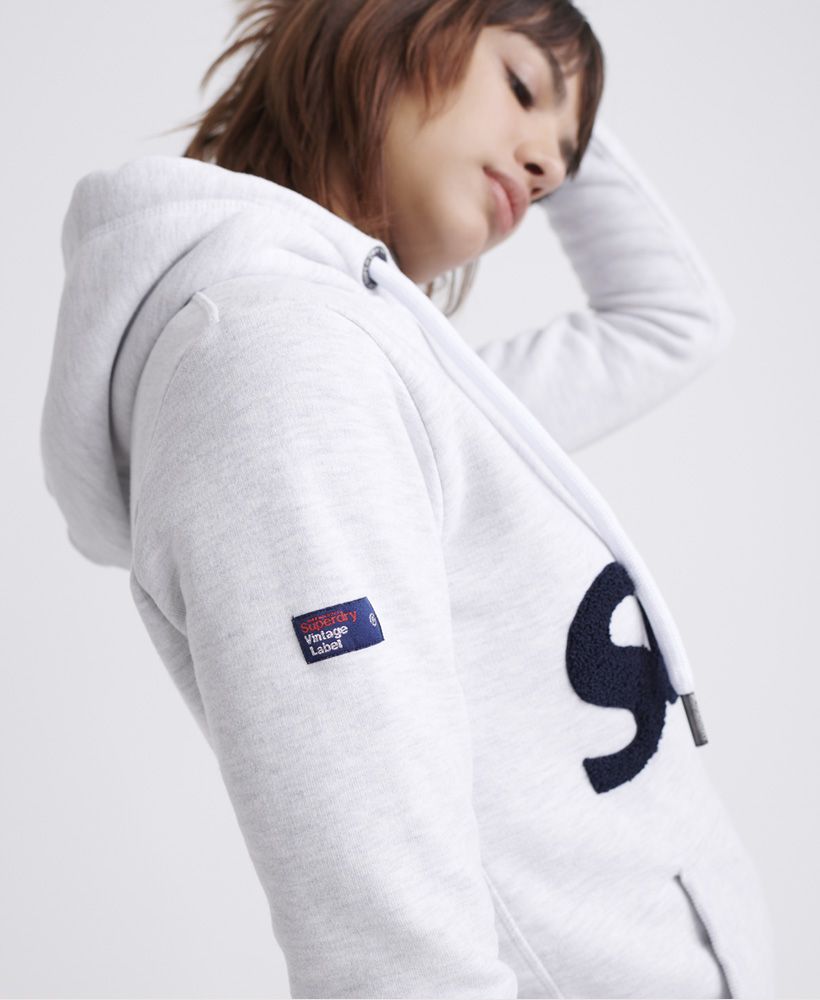 Superdry women's Embroidered classic leaf hoodie. This hoodie features a drawstring hood, ribbed cuffs and hem and a front pouch pocket. Complete with a textured Superdry logo on the chest and a Superdry logo badge on the pocket.