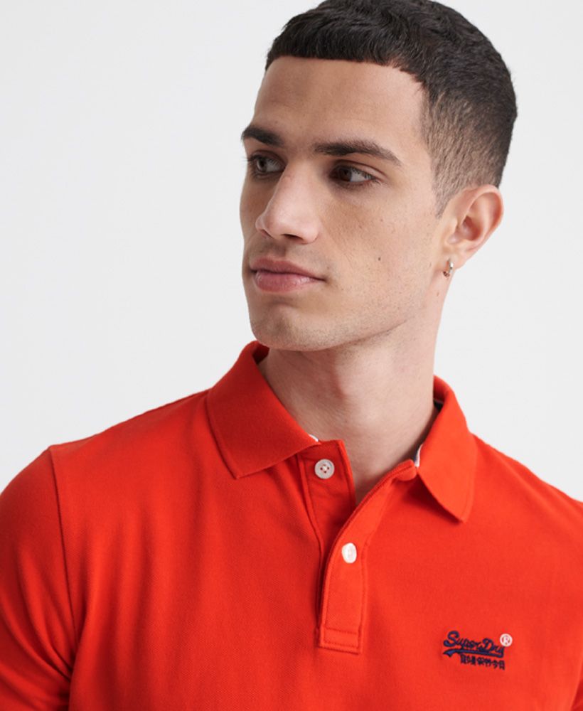Superdry men's Classic pique short sleeve polo shirt. This classic style polo shirt features a half button fastening, short sleeves and reinforced side splits. Completed with a Superdry logo tab on the side seam and an embroidered Superdry logo on the chest.Made with Organic Cotton - Grown using only organic inputs and no artificial chemicals, which leads to improved soil condition, stronger biodiversity and better health among the cotton growers and uses between 60-90% less water to grow. By 2030, all Superdry Cotton will be Organic.Slim fit