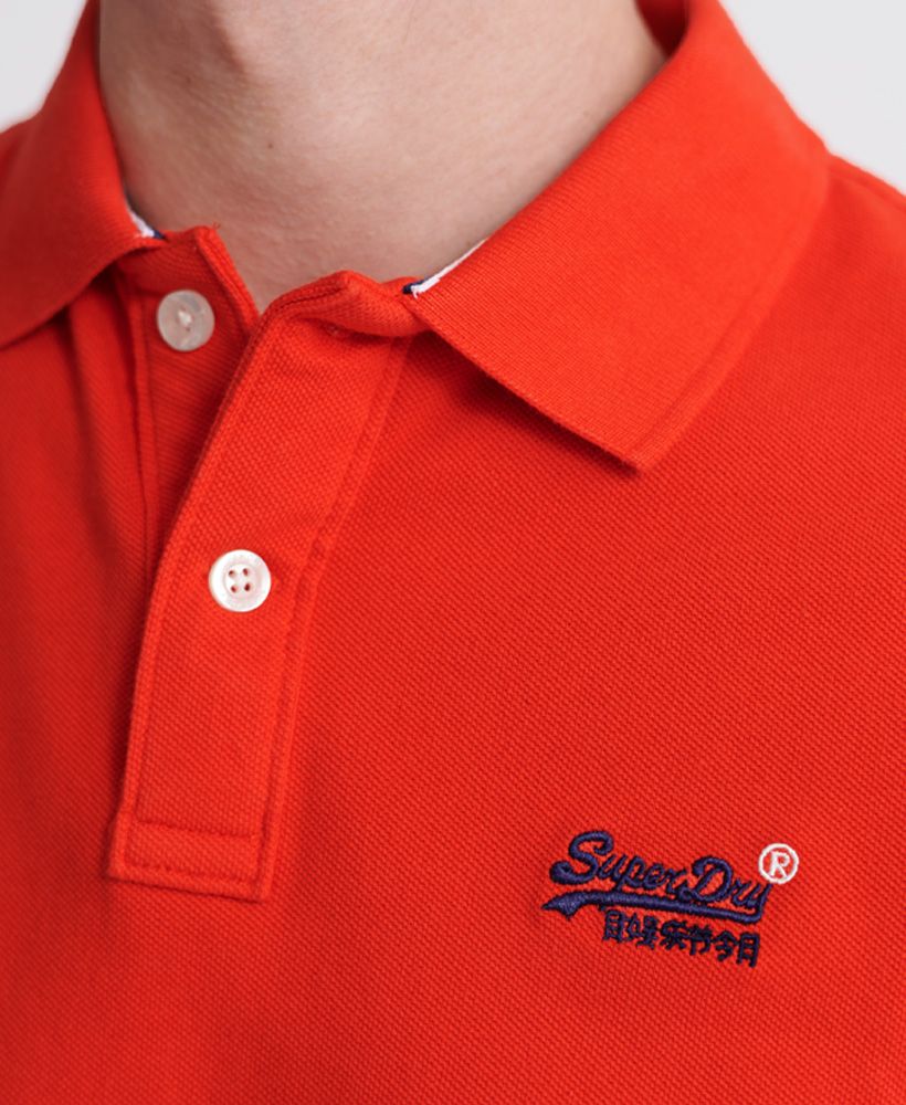 Superdry men's Classic pique short sleeve polo shirt. This classic style polo shirt features a half button fastening, short sleeves and reinforced side splits. Completed with a Superdry logo tab on the side seam and an embroidered Superdry logo on the chest.Made with Organic Cotton - Grown using only organic inputs and no artificial chemicals, which leads to improved soil condition, stronger biodiversity and better health among the cotton growers and uses between 60-90% less water to grow. By 2030, all Superdry Cotton will be Organic.Slim fit
