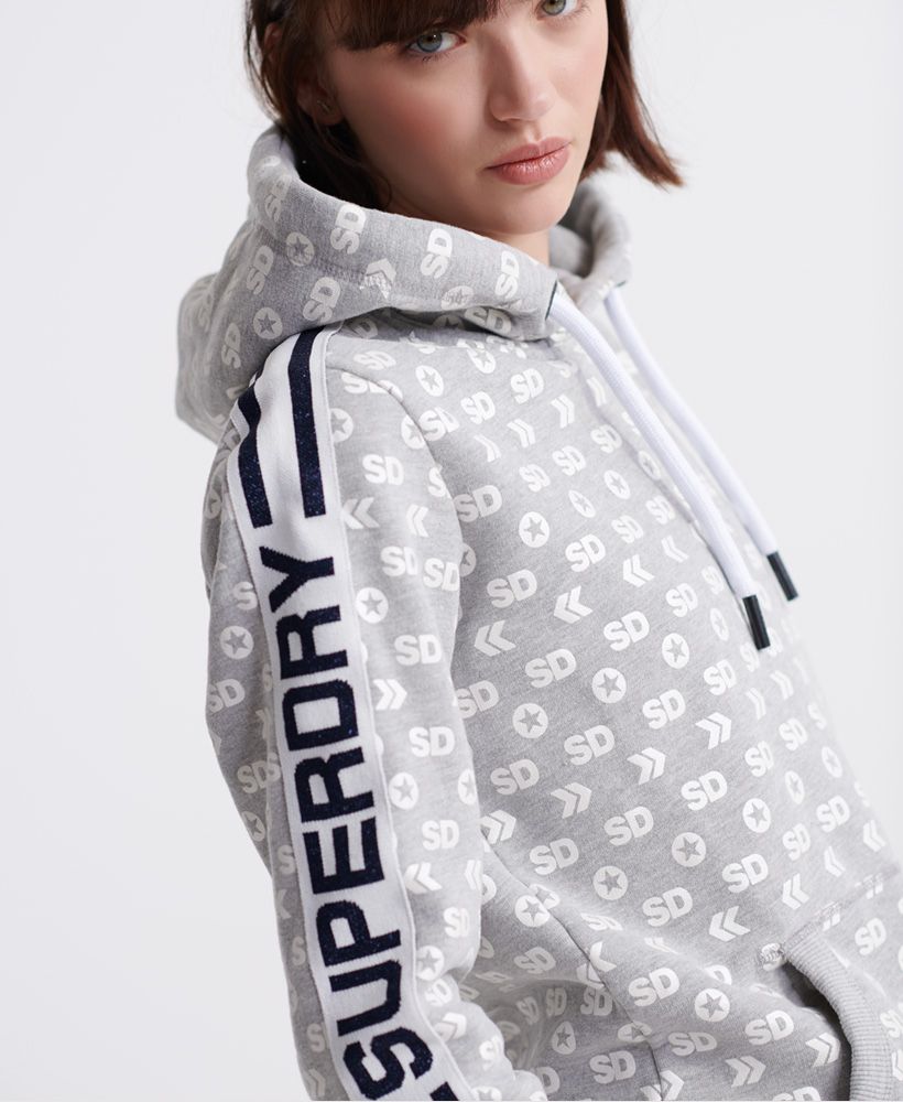 Superdry women's Modern monogram hoodie from the Coral Label range. This hoodie features a drawstring hood, two front pockets with a ribbed trim, cuffs and hem. Complete with an all over Superdry logo design and stripe detailing down both sleeves featuring a Superdry logo. Pair with the matching joggers to complete the look this season.