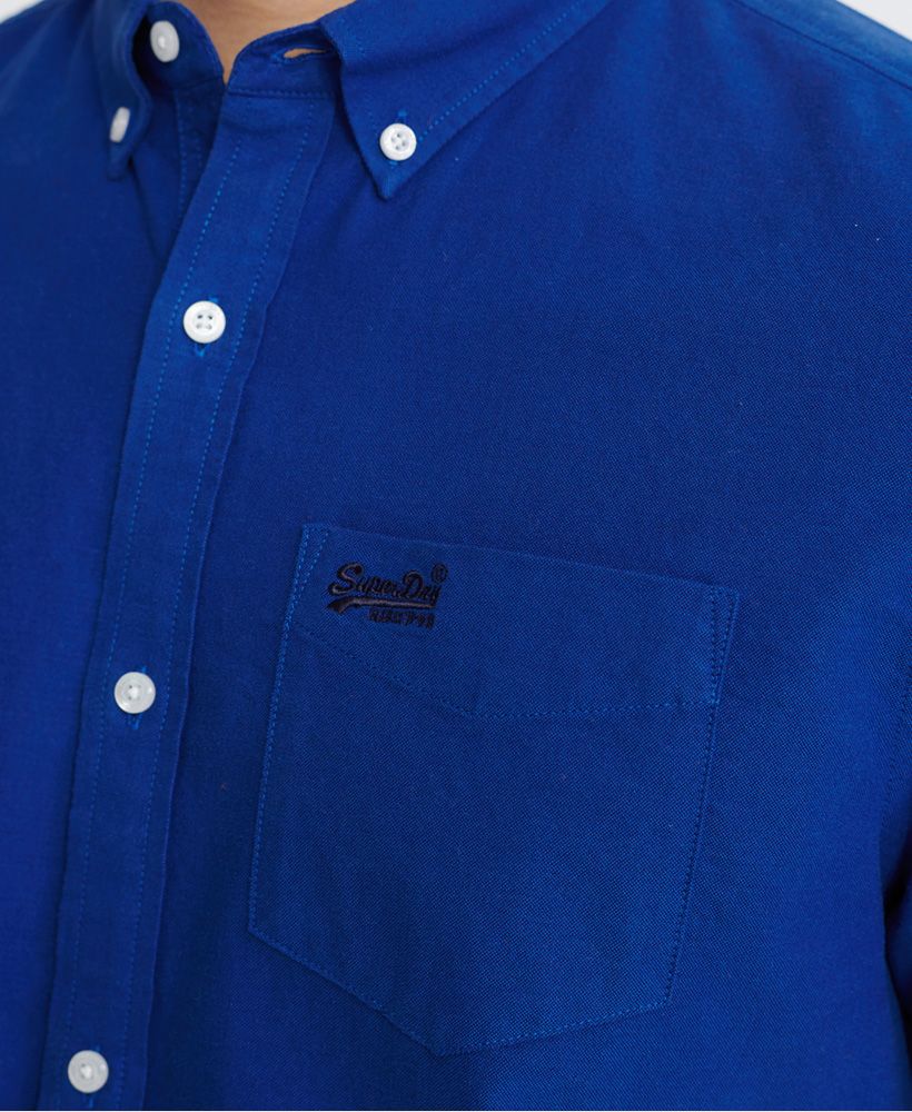 Superdry men's Classic University Oxford short sleeved shirt. A classic shirt featuring a button fastening, button down collar, reinforced side seams, and a single chest pocket. Finished with an embroidered Superdry logo on the chest pocket, and a Superdry logo patch on the placket.