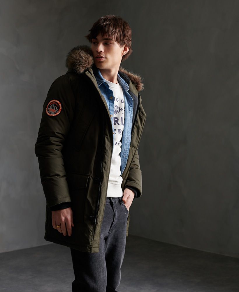 Superdry men's Everest Parka jacket. Your trusty goes-with-everything, beats-the-cold jacket features a four pocket popper design with fleece lining and ribbed cuffs for your comfort. Also featured is a zip and button fastening with a removable faux fur trim on the hood. Both the hood and waistline feature a drawstring to adjust to suit. Complete with an inner pouch pocket and Superdry logo badge on one shoulder, this jacket is this season's must-have.
