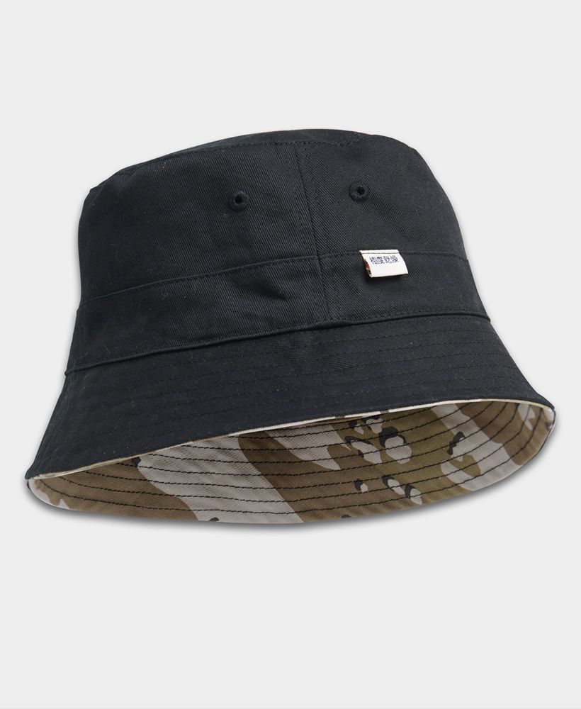 Superdry women's Reversible bucket hat. Go from one look to anther with this reversible bucket hat featuring, stitched eyelet detailling and a choice of two patterns. Finished with a Printed Superdry logo on one side and a Superdry logo tab on the other.