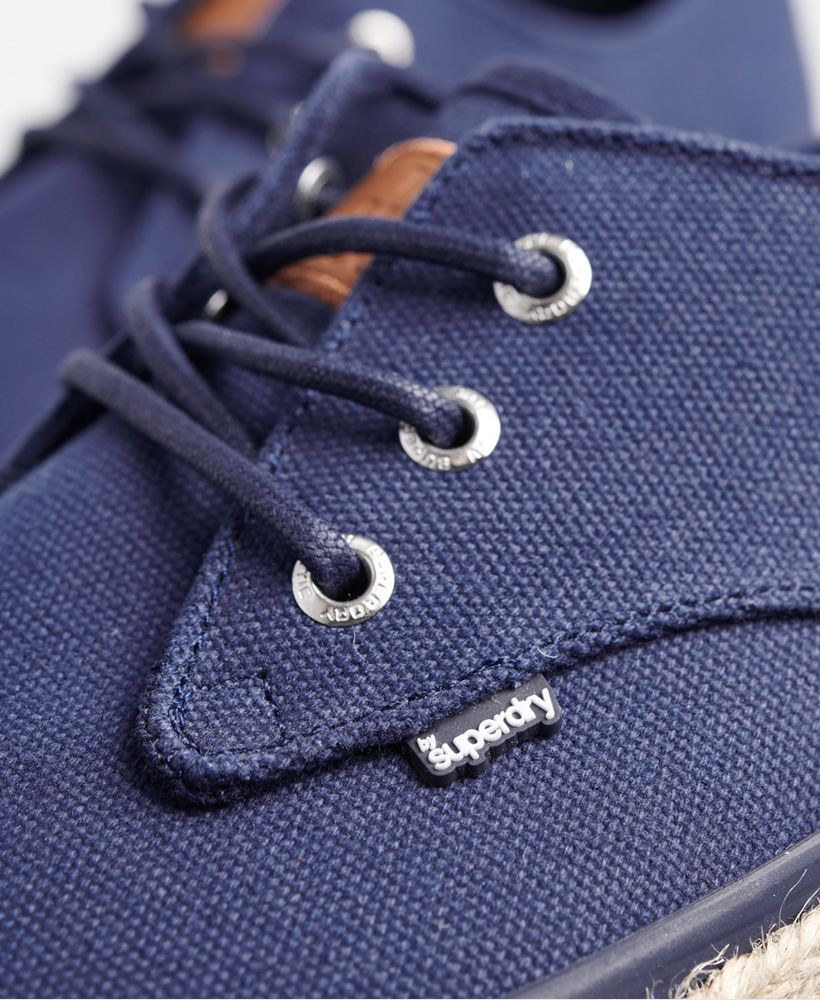 Superdry men's Skipper shoes. These shoes have a woven finish around the sole and feature a three eyelet pair fastening. The Skipper shoes have a Superdry patch on the tongue with debossed branding and are finished with a Superdry logo tab on the side.