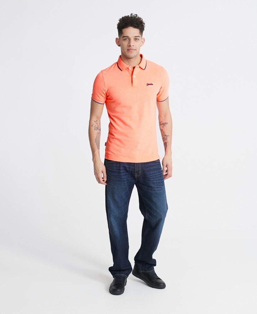Superdry men's Poolside pique polo shirt. Relax your style this season with a classic polo shirt featuring short sleeves, a button up collar, side split on the seams, and a longer hem at the back. Pair with jeans for a casual look, or chinos for a smarter look.Contains Over 60% Organic Cotton - which is grown without the use of artificial chemicals, leading to better soil, 60-90% less water used, and better health for farmers.Slim fit