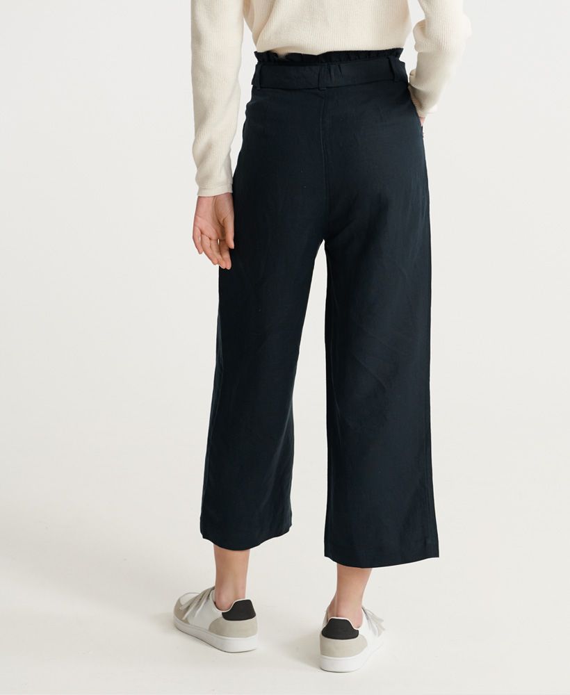 Superdry women's Edit linen trousers. A classic lightweight linen blend, these trousers feature a wide leg design, button fastening, two front pockets and a tie belt with loops for a flattering waistline. Finished with a ruched waistband and metal Superdry logo badge on one front pocket.