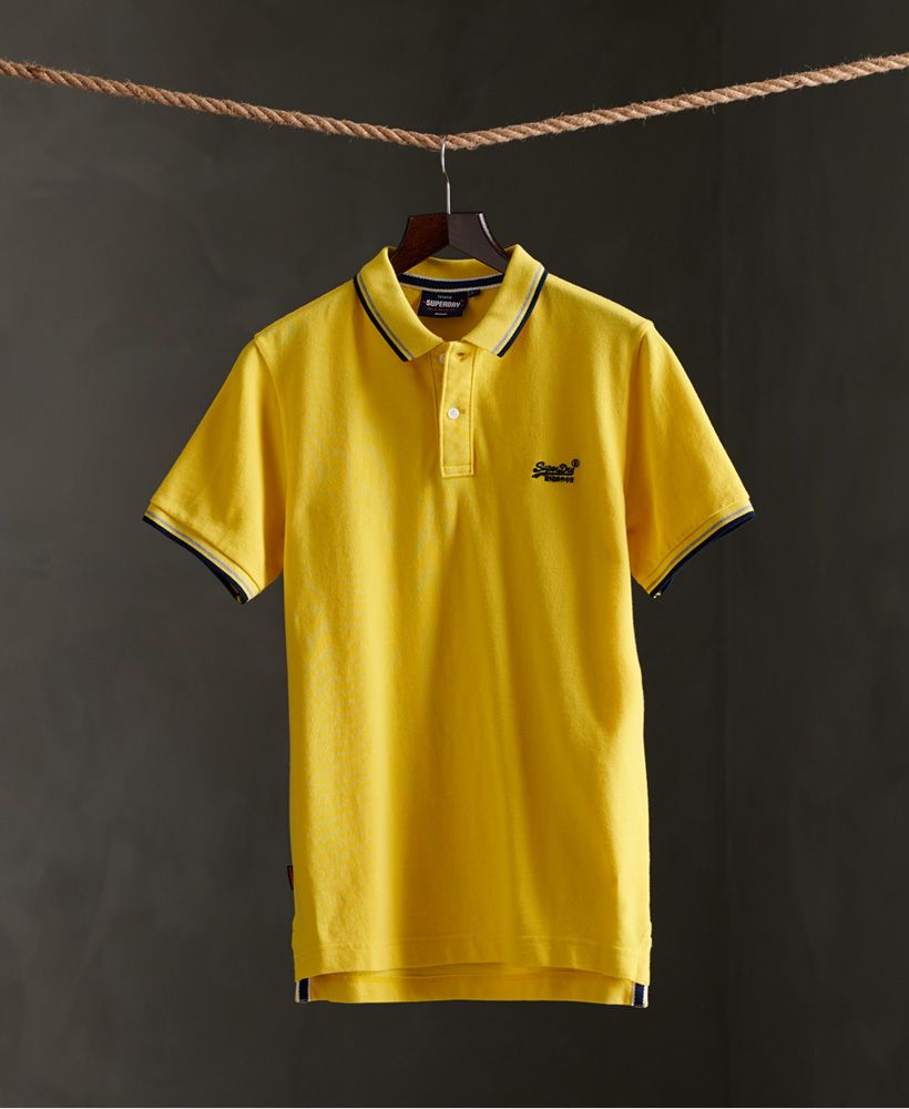 Superdry men's Classic Poolside pique polo shirt. This polo shirt features a single collar with a button fastening, a reinforced split side seam and a ribbed collar and cuffs. Also featured are contrasting colour stripes on the collar and cuffs for added detail. Complete with an embroidered Superdry logo on the chest and Superdry logo tab on one side seam.Made with Organic Cotton - Made using cotton grown using organic farming methods which minimise water usage and eliminate pesticides, maximising soil health and farmer livelihoods.Slim fit