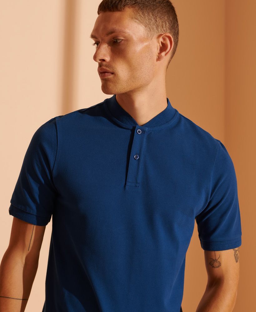 Simple, sophisticated, stylish. Everything you need in an essential polo shirt. The Henley Collar Pique Polo Shirt is a versatile piece that you can mix and match with any outfit.Relaxed fit – the classic Superdry fit. Not too slim, not too loose, just right. Go for your normal sizeOrganic cottonHenley collarShort sleevesButton fasteningRibbed trimsMade with Organic Cotton - Grown using only organic inputs and no artificial chemicals, which leads to improved soil condition, stronger biodiversity and better health among the cotton growers and uses between 60-90% less water to grow. By 2030, all Superdry Cotton will be Organic.