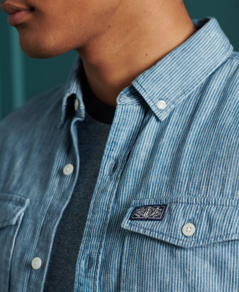 Superdry men's Loom worker shirt. This short sleeved shirt features a patterned design, a button down fastening, a straight collar and two chest pockets. The shirt is finished with a Superdry logo patch on one pocket, and a Superdry logo patch on the bottom of the placket. Pair with jeans or chinos for a smart casual look.
