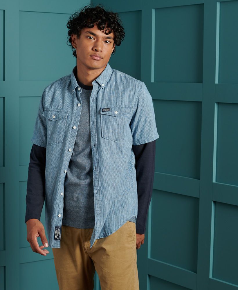 Superdry men's Loom worker shirt. This short sleeved shirt features a patterned design, a button down fastening, a straight collar and two chest pockets. The shirt is finished with a Superdry logo patch on one pocket, and a Superdry logo patch on the bottom of the placket. Pair with jeans or chinos for a smart casual look.