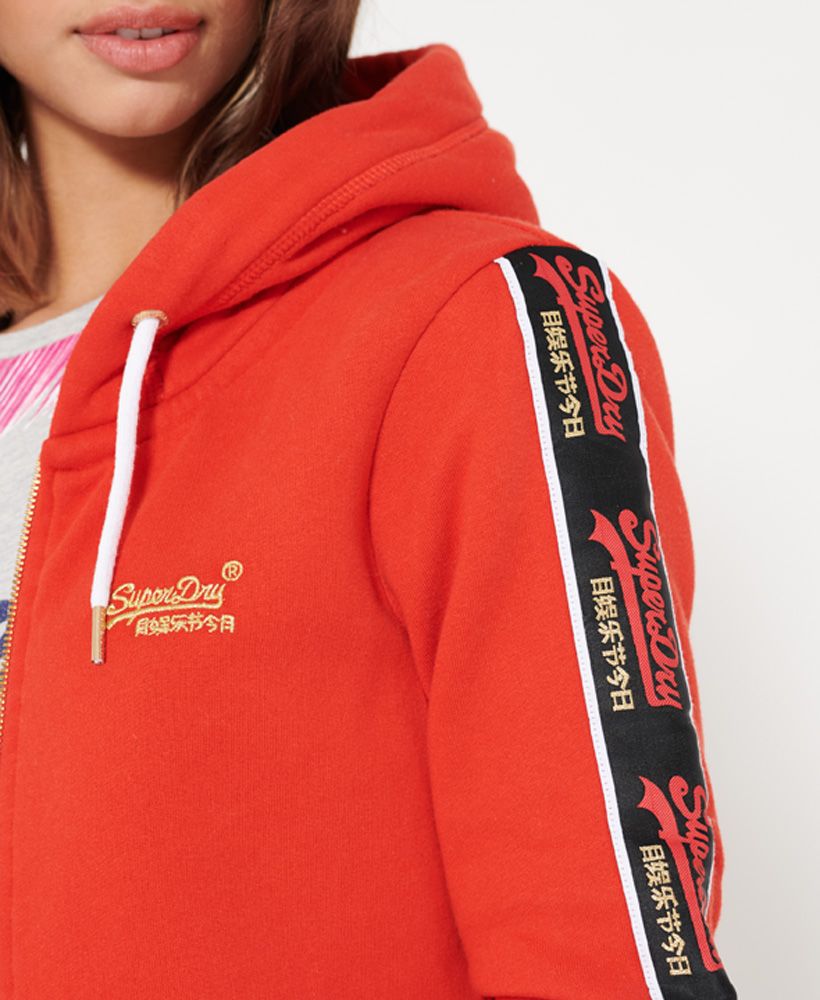 Superdry women's CNY zip hoodie. This hoodie has been inspired by the celebration of the Chinese New Year. This hoodie features a main zip fastening, a drawstring hood, two pouch pockets and ribbed cuffs and hem. Completed with striped Superdry logo detailing down the sleeves and an embroidered Superdry logo on the chest.