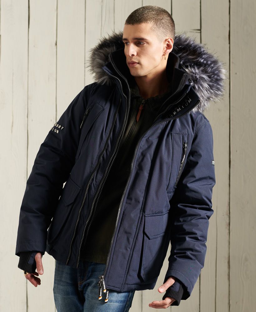 Superdry men's Premium Ultimate downcheater jacket. Part of our premium goods range this downcheater jacket features, a triple zip fastening, a two collar design one with ribbed detailling, four breast pockets both zip and pouch fastening and two front popper pockets with ventilation. Our classic Downcheater also includes ribbed cuffs with thumb-holes, bungee cord adjustable hem, an adjustable hood, removable faux fur trim, an inside hook loop and inner pocket with popper fastening. Our Downcheaters come with a 90/10 premuimum down padding rating, ensuring warmth this season. This jacket is finished with a Superdry metal logo on one arm, a Superdry patch logo on the other arm and the inside placket and finally Superdry branded zip pulls.Superdry is certified by the Responsible Down Standard to confirm that our down filled products are sourced to ensure animal welfare.
