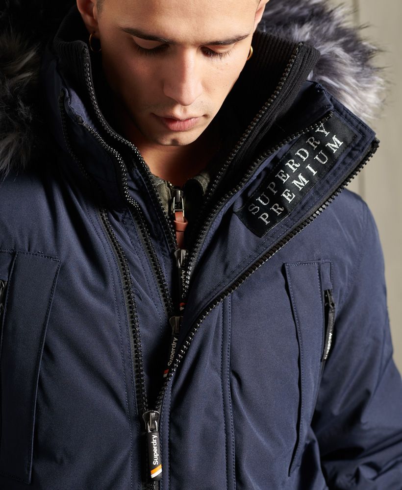 Superdry men's Premium Ultimate downcheater jacket. Part of our premium goods range this downcheater jacket features, a triple zip fastening, a two collar design one with ribbed detailling, four breast pockets both zip and pouch fastening and two front popper pockets with ventilation. Our classic Downcheater also includes ribbed cuffs with thumb-holes, bungee cord adjustable hem, an adjustable hood, removable faux fur trim, an inside hook loop and inner pocket with popper fastening. Our Downcheaters come with a 90/10 premuimum down padding rating, ensuring warmth this season. This jacket is finished with a Superdry metal logo on one arm, a Superdry patch logo on the other arm and the inside placket and finally Superdry branded zip pulls.Superdry is certified by the Responsible Down Standard to confirm that our down filled products are sourced to ensure animal welfare.