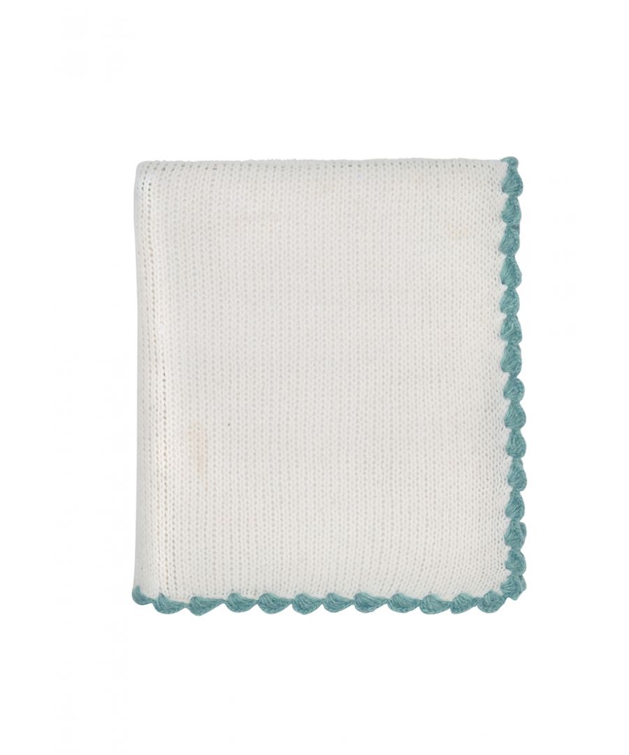 The knitted throw in ivory with scalloped edging in a teal pop adds a desirable cosy charm.