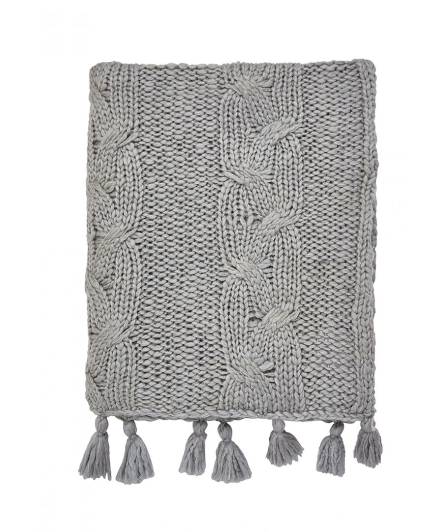 A chunky cable knit throw, finished with grey tassels at either end.