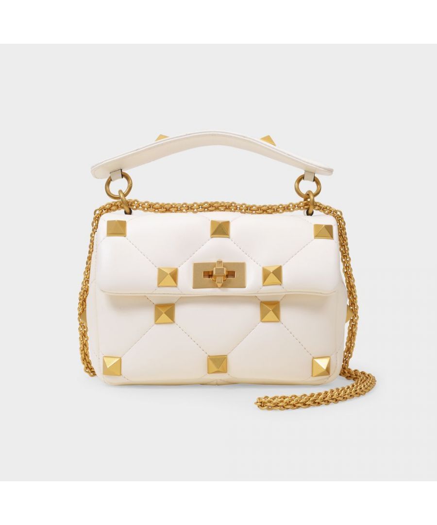 Add a daring touch to your look with this piece from Valentino Garavani. We love the quilted ivory leather, gold-tone signature studs, for their chic-with-an-edge feel. Wear it with a long, beige dress and a pair of high heeled sandals. Shoulder strap : 110 cm. Worn two ways - One top handle and One adjustable. detachable shoulder strap. Material : Smooth Lambskin. Lining : Leather. Colour : Beige - 98 Ivory. Closure : Turnlock Closure.