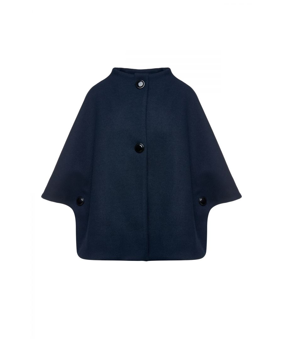 This navy blue winter cape is crafted in faux mouflon style fabric. It has short sleeves and a round neckline. The cape fastens in the front with 2 big decorative buttons as well as one on each side. It has a subtly rounded hem. This cape can be worn with casual outfits or with dressier ensembles.