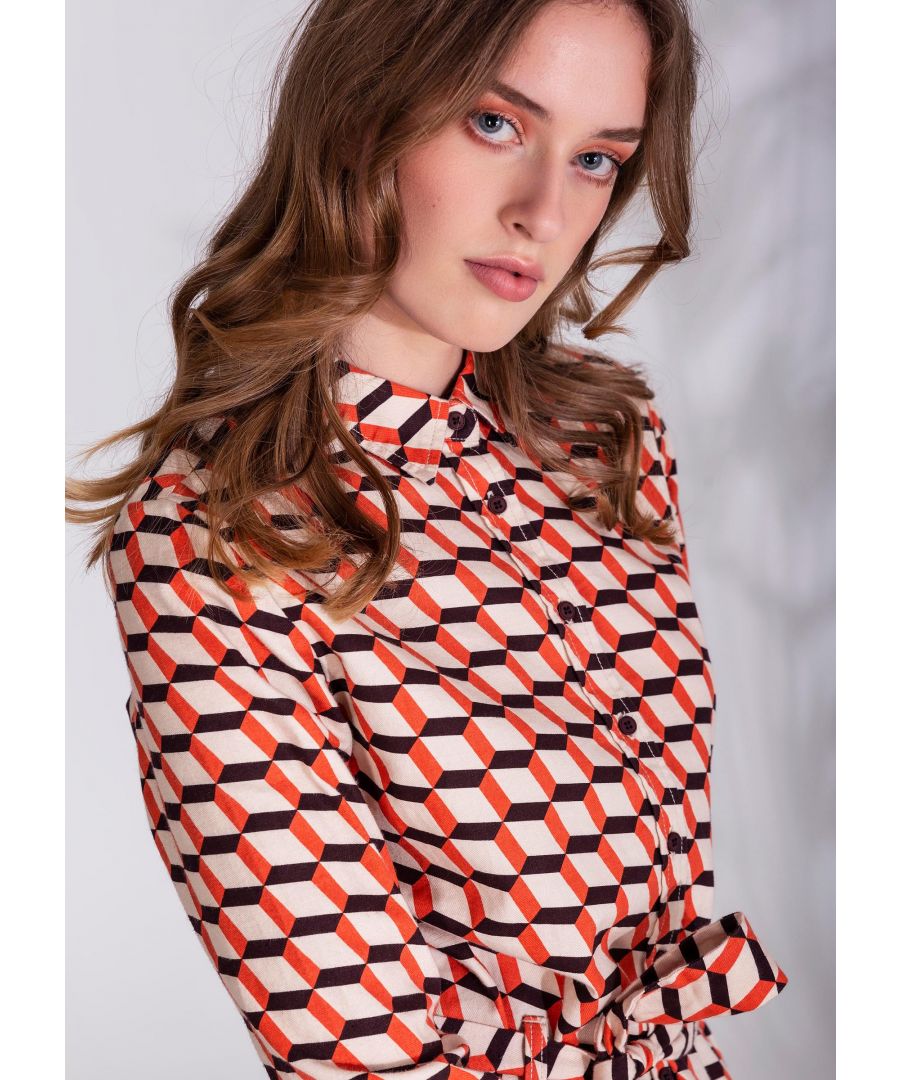 Overhemdjurk met geometrisch patroon in oranje, bruin en wit met lange mouwen en knopen. De jurk heeft een bijpassende riem die de taille accentueert. De contasterende gestreepte riem met metalen sluiting is als losse accessoire verkrijgbaar.