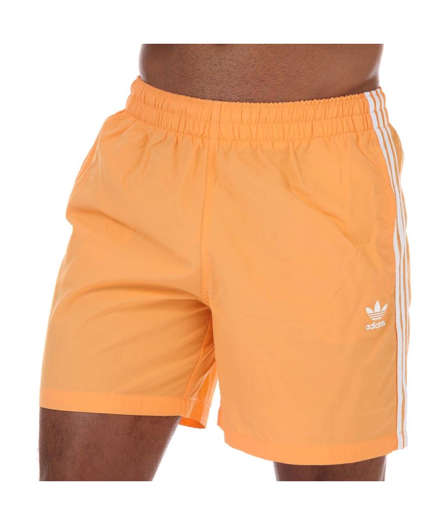 Mens adidas Originals Adicolor Classics 3- Stripes Swim Shorts in orange.- Elasticated waist with inner drawcord.- Front pockets.- Inner mesh briefs.- Lightweight  quick-dry fabric.- Regular fit.- Shell: 100% Polyamid (Recycled). Inner Brief: 100% Polyester (Recycled). - Ref: GN3525