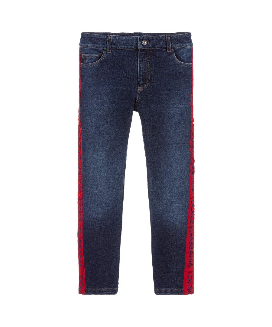 This Dolce & Gabbana Kids Jeans in Navy, is made from a washed and wornlook cotton to give it the appearnce of denim jeans. Features a red ribbon taping that runs along the outside of the legs, whilst featuring the brands embroidered blue logo.