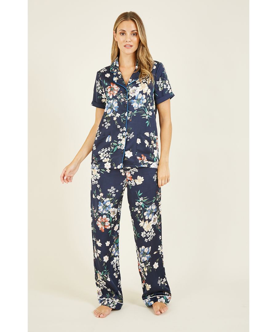 Sleepwear, but don't sacrifice style. This luxurious silky satin three piece pyjama set from Yumi boasts a bright and bold floral print complete with contrast white piping. The top comes with a button through fastening, collar and short sleeves, with loose fitting trousers and a satin bag to match.