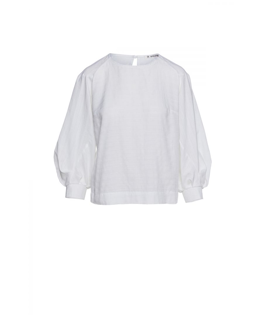 Wit top met driekwart raglan bisschopmouwen. Ronde hals die aan de achterkant met een knoop wordt vastgemaakt. Figuurnaden bij de buste. Recht model.