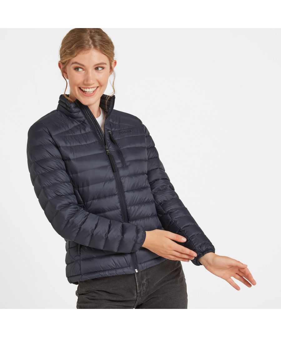 Perfect for adding a layer of warmth without any bulk, our Drax down filled womens jacket is soft and silky to the touch, incredibly light and packs down small into a zip up inside pocket. You'll have no trouble finding room for it in your case when you go away, and it also makes a handy travel pillow. This padded jacket gets its incredible warmth from naturally insulating duck down that traps heat without being bulky. Sleek panelling and a high neck creates a flattering fitted silhouette and it feels as good as it looks with details like a soft chin cover over the top of the zip. Designed to squish down really small, then spring back into shape, Drax has roomy side pockets protected by an elasticated flap, light elastic at the cuffs and small toggle adjusters at the hem keep the chill out. Designed in Yorkshire, where we always need layers, our Drax womens jacket is ideal for wearing over a top when it's only a bit chilly or layering under a coat when the wind is howling. Reflecting our Spen Valley ethos of Truth Over Glory, it has a TOG24 logo proudly printed on the chest.
