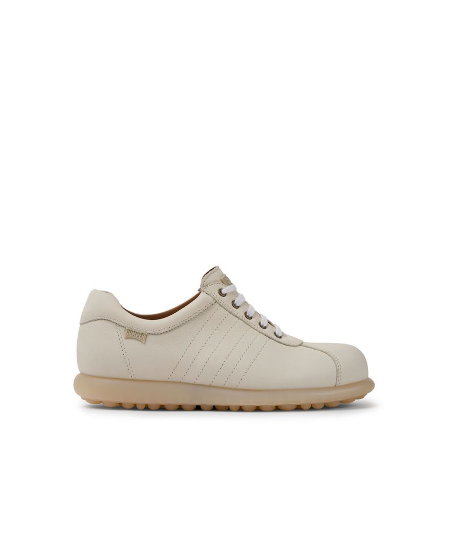 White shoe for women. 100% leather upper with laces. 100% beige rubber outsole. \n\nA Little Better, Never Perfect \n\nOur Pelotas women’s shoes are our most iconic Camper style. With an unmistakable, sport-inspired outsole comprised of 87 spheres, our Pelotas - Spanish for 