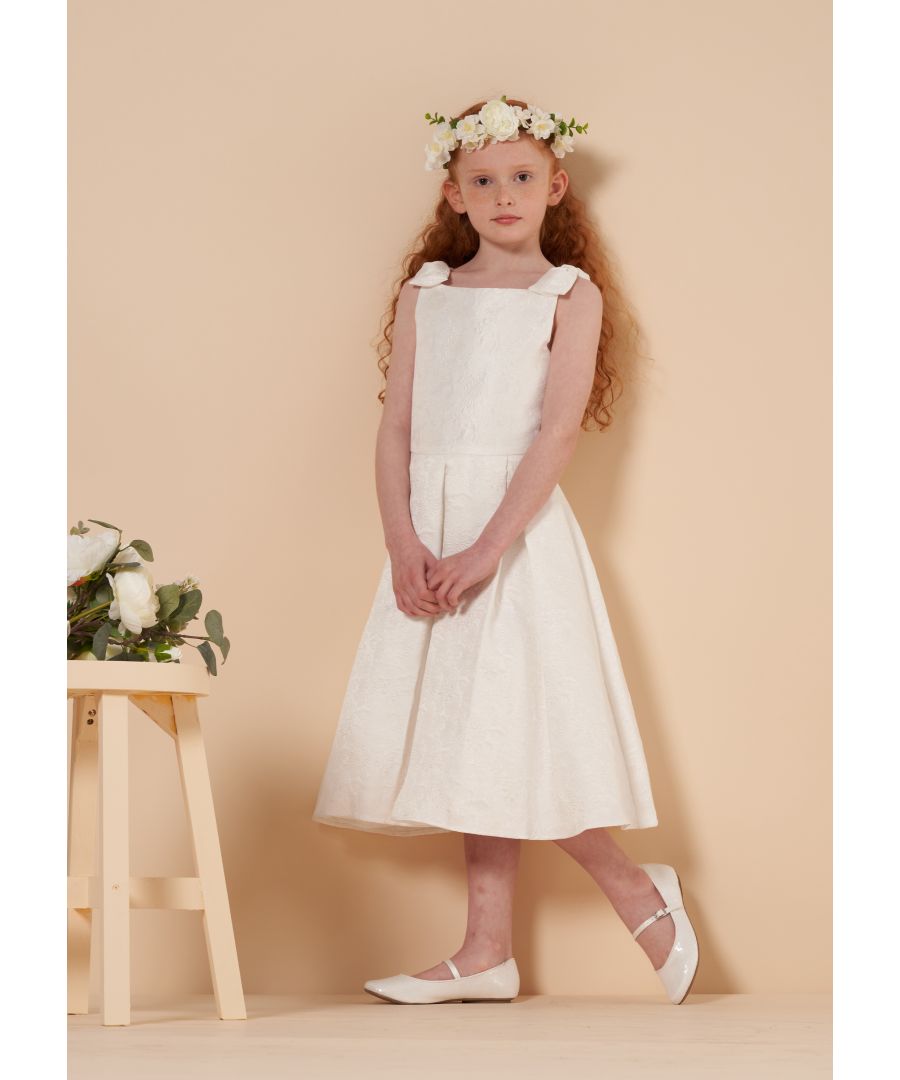 A beautiful printed ivory girls jacquard dress with bow shoulder detail. The pleated waist detail adds shape and the high neckline make this dress an ideal choice for weddings and kids parties. The subtle floral print and elegant design of the Aurelia dress means it’s perfect as a bridesmaids or a flower girl dress. Any little girl at a wedding or party would look stunning in this. Available in sizes 3 YRS to 12 YRS all of your flower girls or bridesmaids can wear a matching girls jacquard dress and will feel extra special when doing so. Angel & Rocket cares about the environment  so this girls jacquard dress is made from recycled polyester.  Colour: Ivory   About me: 100% polyester   Look after me: machine wash on a delicate cycle  cool iron  wash with similar colours. Do not tumble dry.