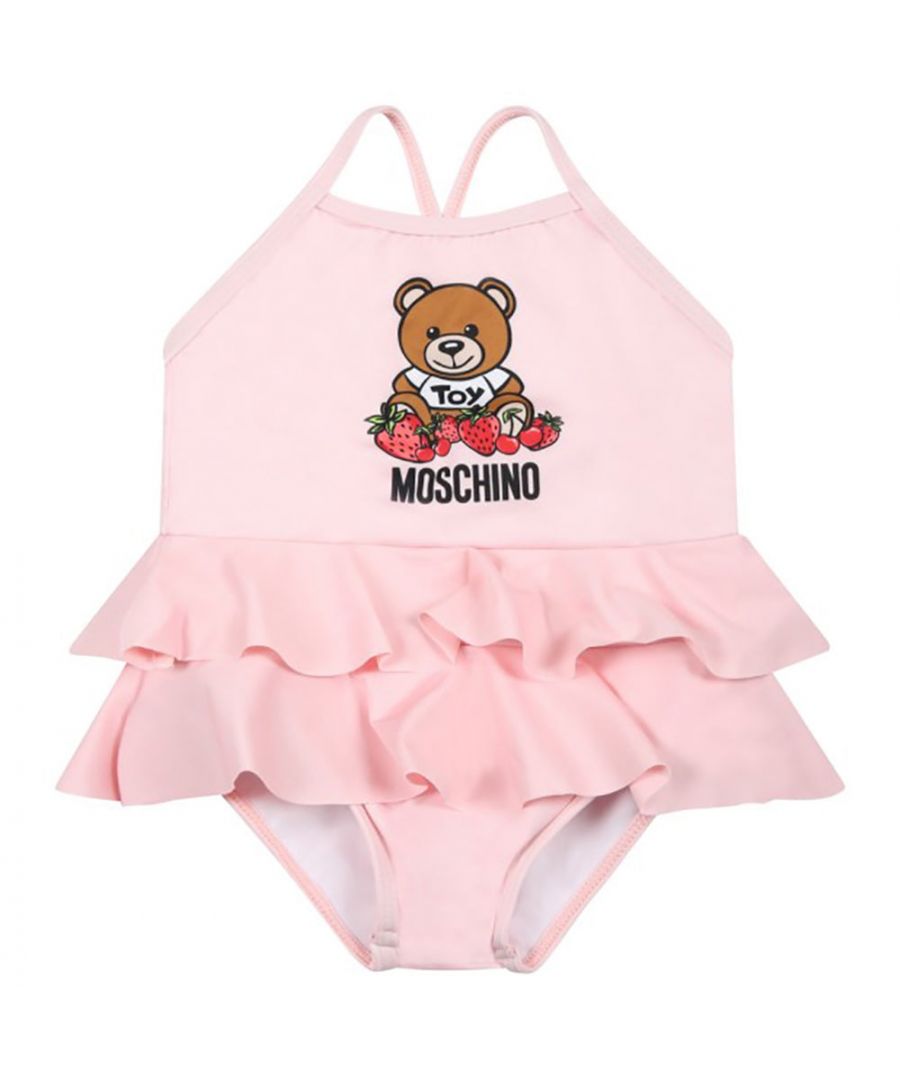 This Moschino baby girls pink swimsuit consists of crossed straps on the back and ruffles on the bottom. It’s embellished with teddy bear, logo and strawberries on the front.\n\n77% Polyester, 23% Elastane. \nMachine wash at 30°C.