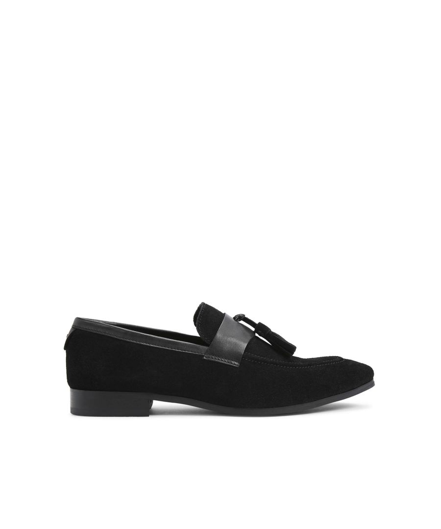 The Stevie Tassel is a formal slip on shoe in black suede. The vamp is topped with two tassel details.