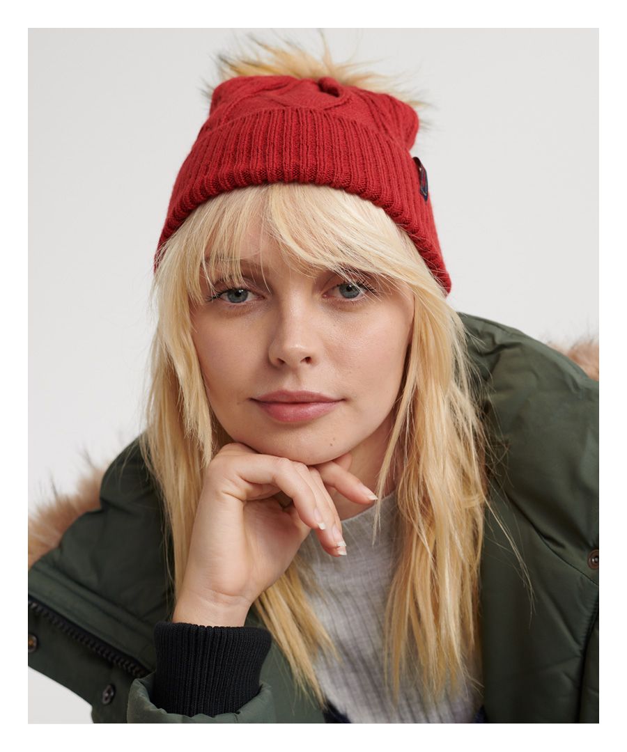 Superdry women's Lannah cable beanie. The Lannah cable beanie is a staple winter wardrobe piece in the colder months, featuring a cable knit design, faux fur bobble and ribbed turn-up hem. Finished with a Superdry logo tab on the hem.
