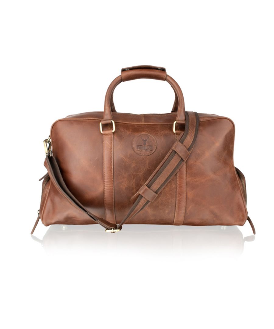 This is a luxurious and new leather holdall from Woodland Leather. No less than 20” in length this holdall has twin handles and a comfort grip for easy carry. Adjustable and matching shoulder strap which is removeable. This holdall is unique in that it has two side shoe compartments - an added advantage for easy access and separate from the main bag. This holdall has a central zip compartment which opens easily providing full access to the bag. A further central zip lining allowing for extra storage and expansion. An extra side zip on the outside of the bag which is convenient for documents or keys. Metal feet for extra support. Two versions one is a full leather and the other is a canvass mix with contrast leather. Dimension: H(28.0cms), L(54.0cms), W(26.0cms) .