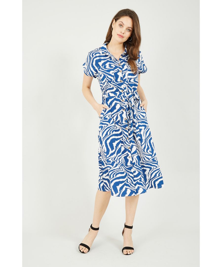 Als je er klaar voor bent om op te vallen, trek dan deze overhemdjurk met zebraprint aan.  De opvallende blauw-witte print en chique overhemdpasvorm is een winnende combinatie. De ceintuur in de taille, korte mouwen en midi-lengte zorgen ervoor dat je zeker zult opvallen in deze statement-jurk. Combineer hem met leer voor een edgy look, of ga voor opvallend met een vleugje kleur op je schoen en handtas.