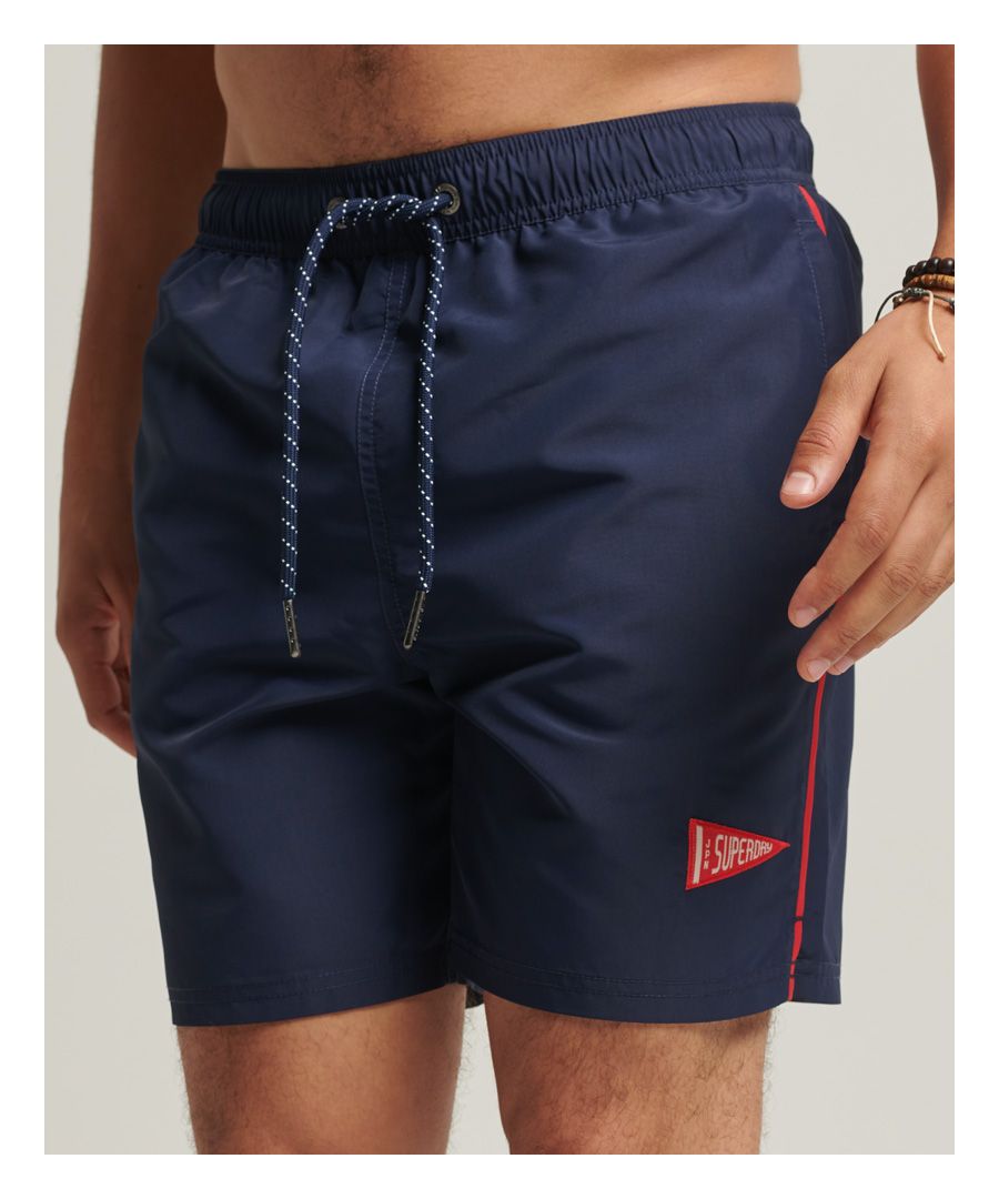 Get yourself ready for the pool and look great when you're there. The Vintage Varsity Swim Shorts will inject a touch of classic college-style into your pool or beach look.Standard fit – the classic Superdry fit. Not too slim, not too loose, just right. Go for your normal sizeElasticated waistband with drawcord fasteningTwin side pocketsContrast pipingSplit side seamsSingle back pocketSupportive mesh linerVarsity inspired logo patchesBy 2050, there will be more plastic in the ocean than fish. Help save plastic from polluting the earth. Wear this instead. This new swimwear fabric is made from 100% recycled post-consumer waste.#GrowFutureThinking