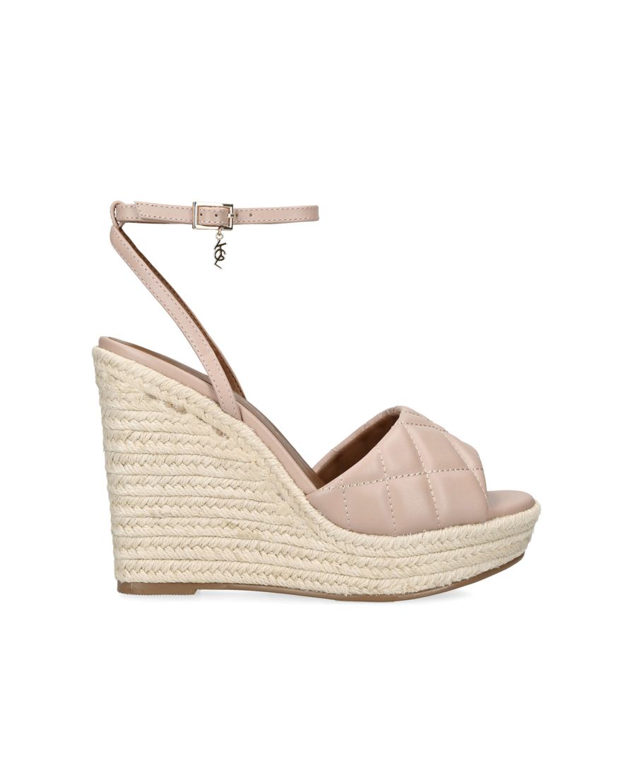 The Kurt Geiger London Brixton Wedge is a wedge heel. The upper is in a blush leather with overstitch quilt across the toe strap. There is a small gold tone KGL charm on the buckle. The heel sits at 10.5cm.