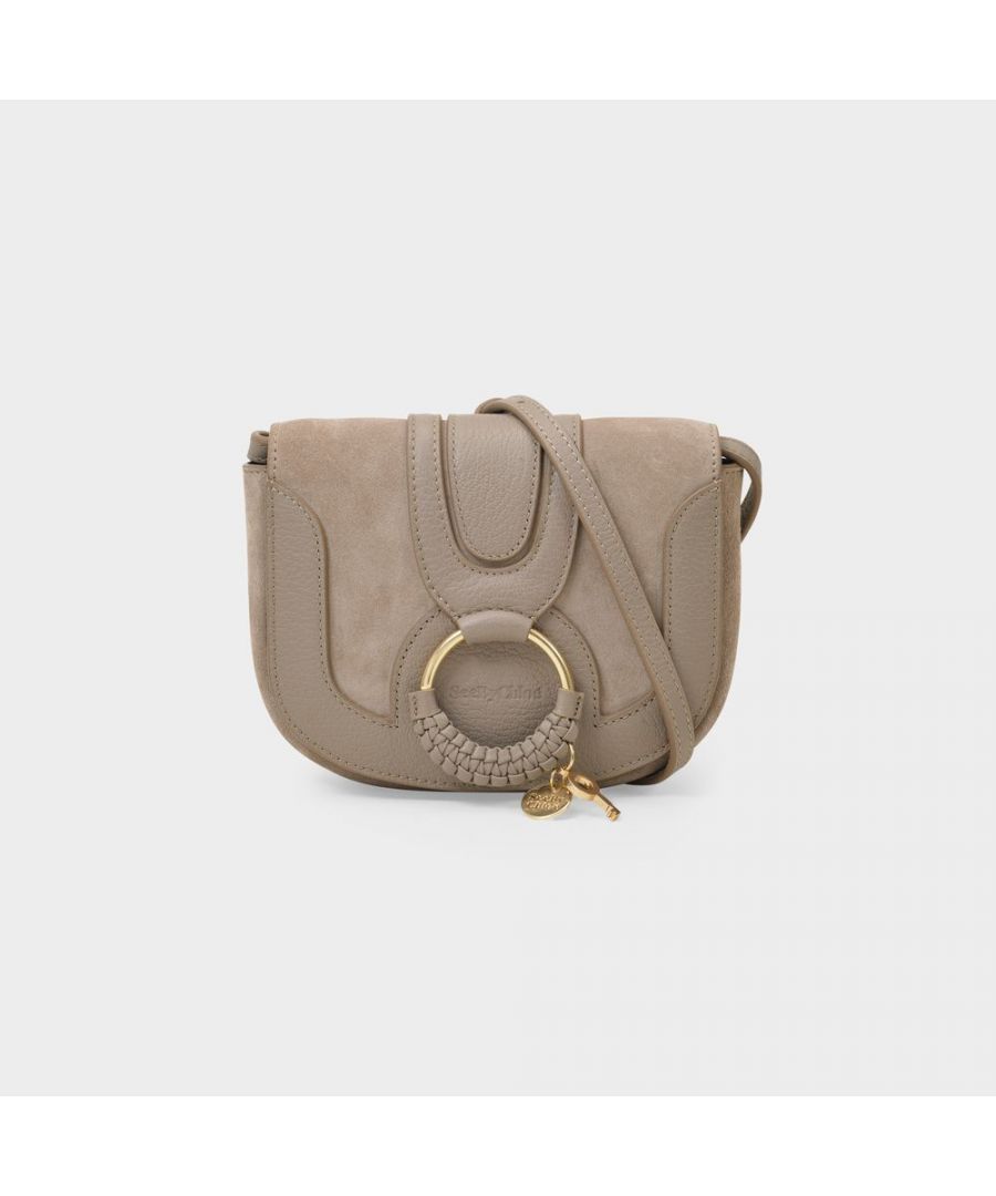The now-cult Hana from See by Chloé has a free, boho 70's feel. It comes in a crossbody version in luxurious grey leather, and features all of the label's signature elements, like the gold-coloured ring and woven detail. Wear it very day, with a long flowery dress, oversize sunglasses and flat leather sandals to highlight its hippie-chic, retro feel. Shoulder strap 100 cm. Worn crossbody - one adjustable strap. Material: cowskin. Lining: cotton. Colour : Gris - Motty Grey. Closure : press button flap. Interior : one flat pocket.