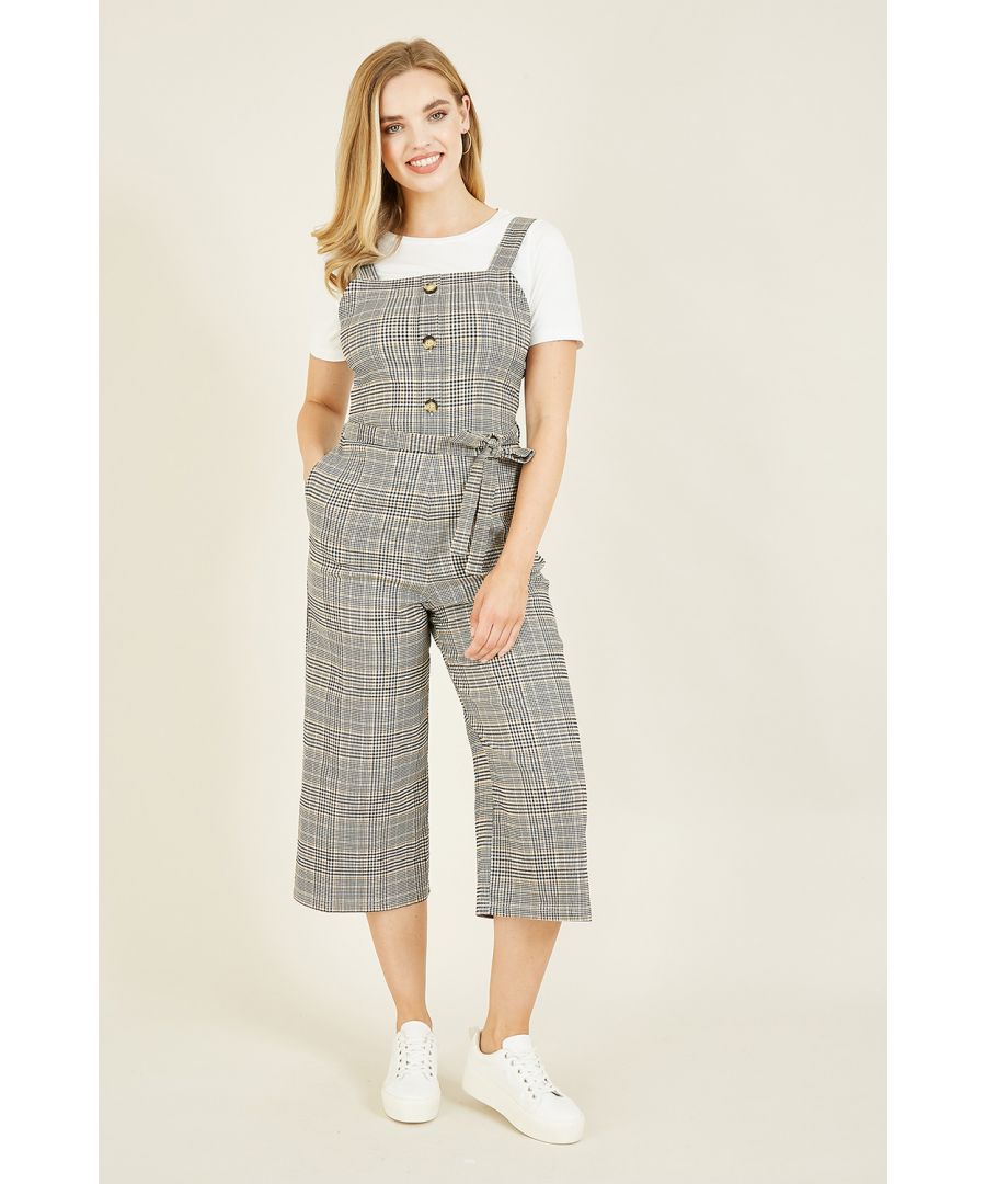 Wat dacht je van deze pasvorm voor het nieuwe seizoen? Deze tuinbroek-jumpsuit heeft brede bandjes, opvallende knopen, een knoopceintuur in de taille en brede culotte-pijpen van stretchmateriaal. Perfect als laagje over een simpel T-shirt - maak je look compleet met een leren jas en oorringen.