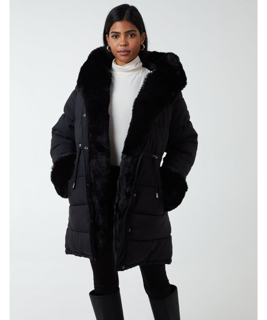 Face the cold British weather days with this Faux Fur Coat in black colour. This comfy and warm coat is padded with a furr detail, has side pockets, fastened with a zip & button front, and a hoodie to protect on rainy days. Layer this coat on top of any outfit of your choosing and boots. 