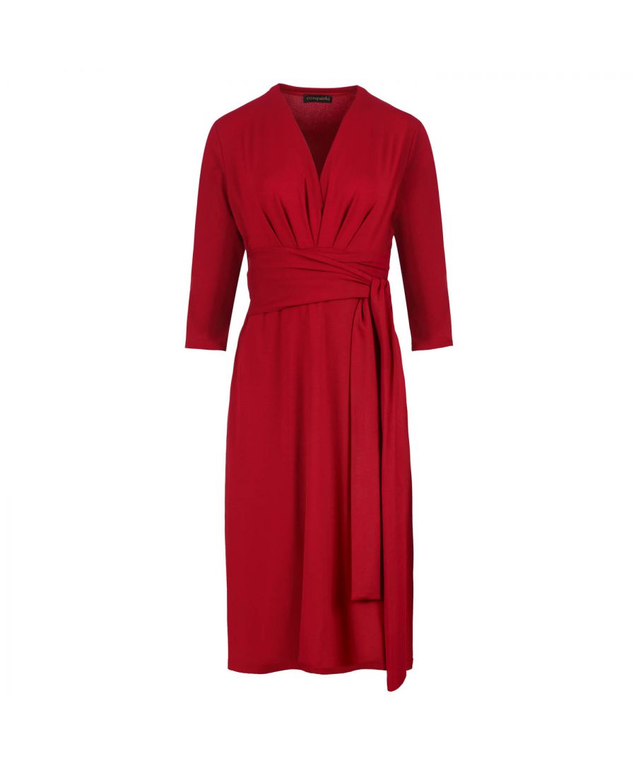 Red dress in stretch jersey fabric, viscose-elastane. ¾ sleeves with a deep V neckline with pleats on the left and right. Seam detail under the bust with pleats below. Belt in the same fabric fastened at the sides. Empire line with an A line silhouette. Knee length.